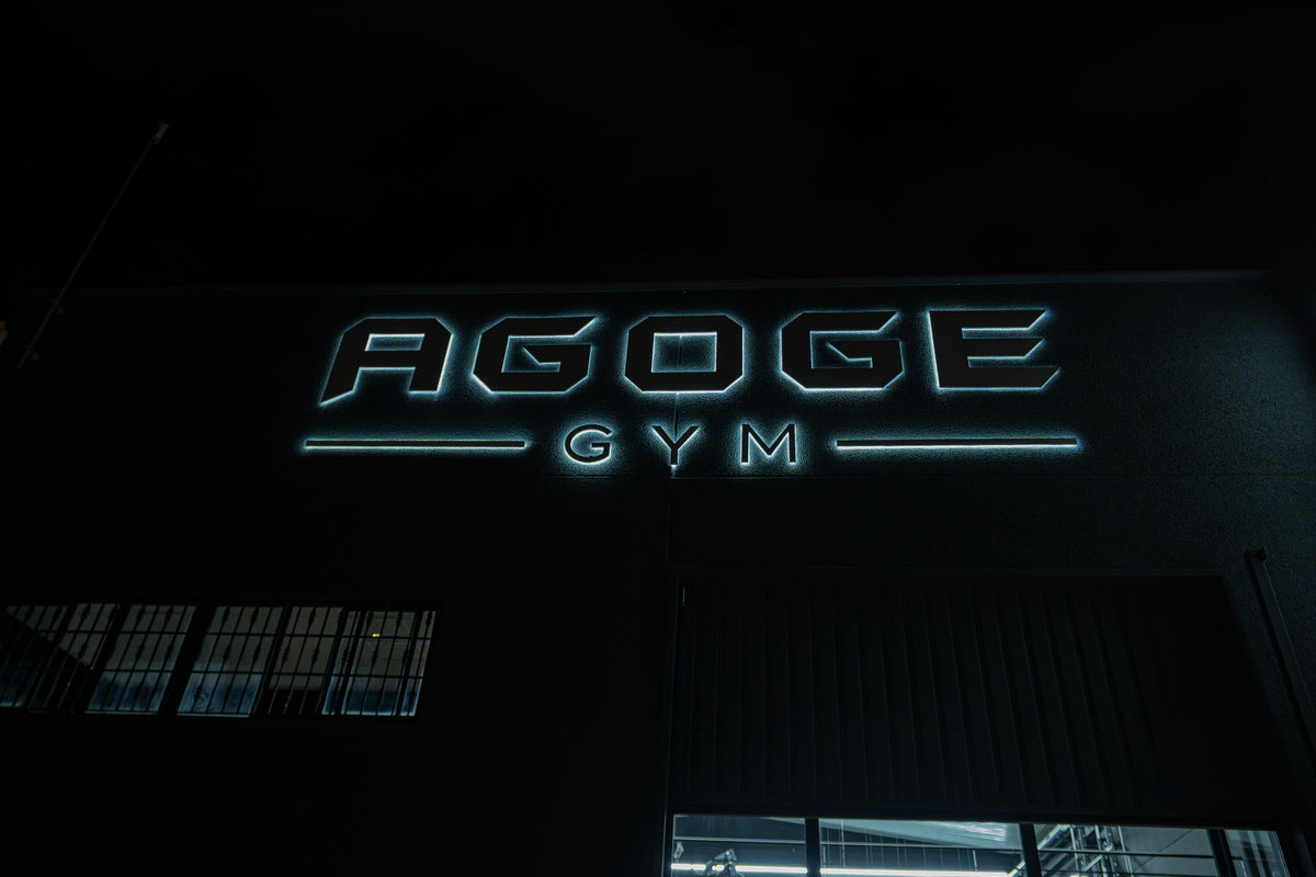 Fachada de AGOGE GYM de noche con el rótulo iluminado